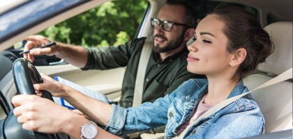 Smiling learner driver at the wheel with an instructor